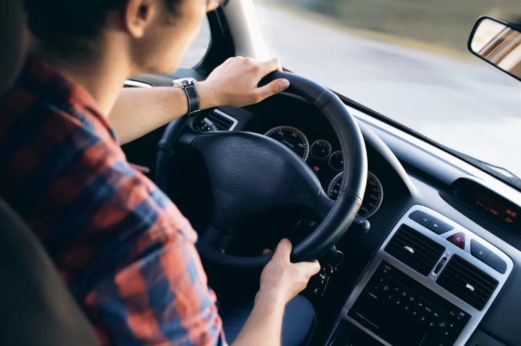 Homme tenant le volant de sa voiture 